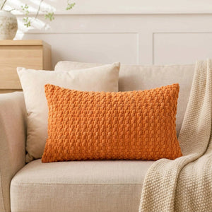 housse de coussin rectangulaire en maille texturée orange sur un canapé en lin