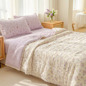 Couette d'été à imprimé floral violet et bordure en dentelle sur un lit