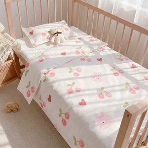 Parure de lit bébé motif cerises roses installée sur un berceau