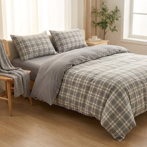 Parure de lit à carreaux grise dans une chambre cocooning avec chaise en bois et plaid