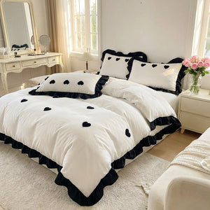 Parure de lit brodee coeur noir dans une chambre feminine elegante avec fleurs et miroir