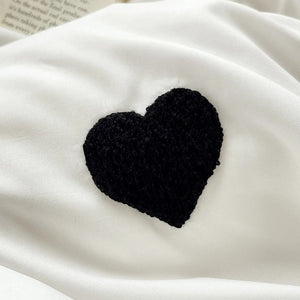 Gros plan sur le coeur brode noir sur le tissu blanc de la housse de couette