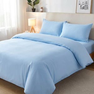 Parure de lit unie bleu sur un lit avec lampe de chevet dans une chambre apaisante