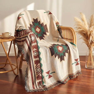 Plaid bohème à franges motif aztèque drapé sur un fauteuil en rotin
