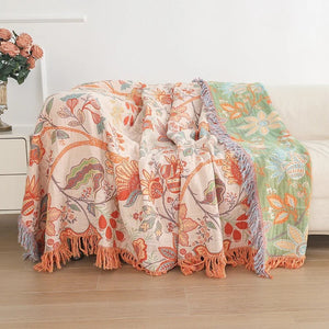 Couverture en coton réversible à motifs floraux orange posée sur un canapé