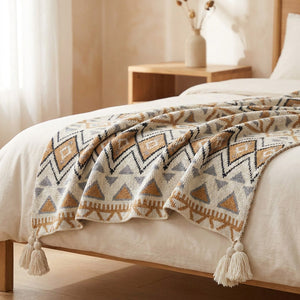Plaid boho à franges déposé au pied d un lit dans une chambre chaleureuse