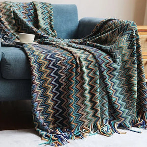 Plaid boho turquoise à chevrons avec longues franges vu de près sur un canapé