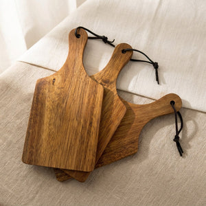 Trio de mini-planches à découper bois acacia disposées sur surface en lin naturel