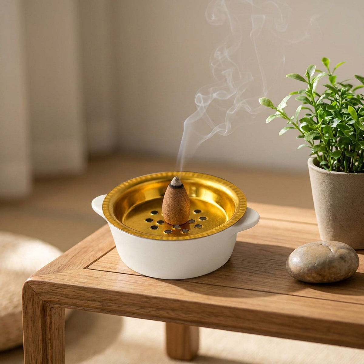 Porte-encens céramique blanche sur une table de méditation avec une plante verte
