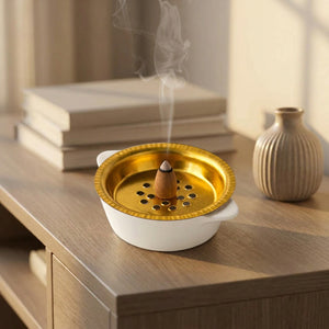 Porte-encens céramique blanche sur une console avec des livres et un vase