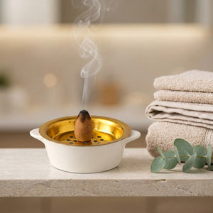 Porte-encens céramique blanche sur une étagère de salle de bain avec serviettes