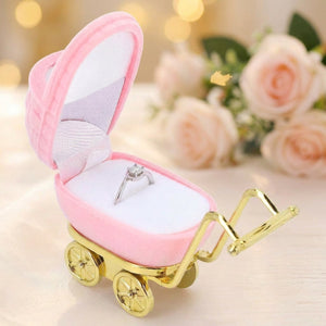 Coffret à bijoux landau rose en velours avec bague solitaire sur fond clair et roses pâle