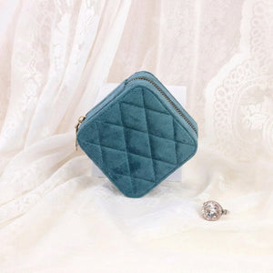 Boîte à bijoux en velours bleu canard fermée posée sur tissu en dentelle avec bague
