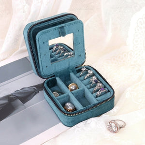 Boîte à bijoux bleu canard ouverte avec miroir et bagues rangées dans les compartiments