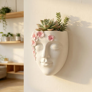 Pot mural visage en résine dans un salon bohème avec succulentes et fleurs roses