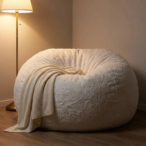 Pouf géant blanc dans un coin cocooning avec plaid et lampe chaleureuse