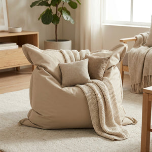 Pouf géant beige avec plaid et coussins dans un salon cosy