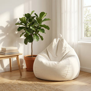 Pouf poire blanc cassé installé dans un coin salon près d'une fenêtre avec plante verte
