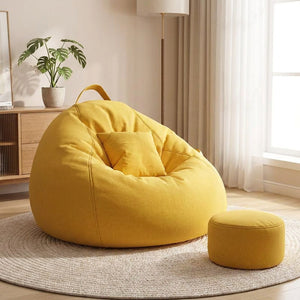 Pouf géant fauteuil poire jaune moutarde garni avec coussin et repose-pieds assortis dans un salon lumineux