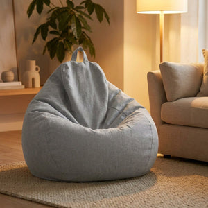Pouf poire gris clair dans un salon moderne eclaire par une lampe chaleureuse le soir