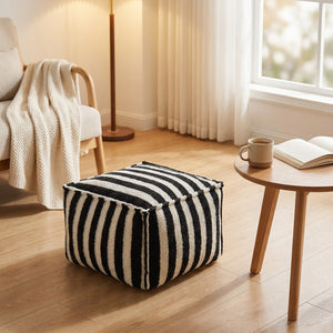 Pouf rayé noir dans un coin lecture cosy près d'une table basse en bois