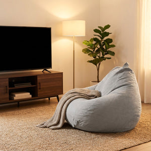 Pouf paresseux tatami gris installé dans un coin salon près d'un meuble TV