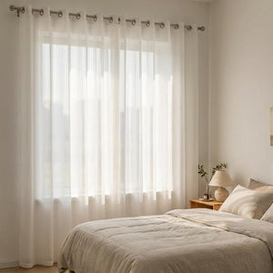 Voilage transparent rayé suspendu à une fenêtre de chambre dans la lumière du matin