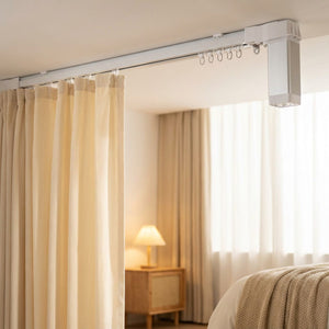 Rail de rideau électrique au plafond d'une chambre avec rideaux crème tirés le matin
