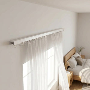 Rail de rideau blanc fixé au mur d'une chambre avec voilage blanc