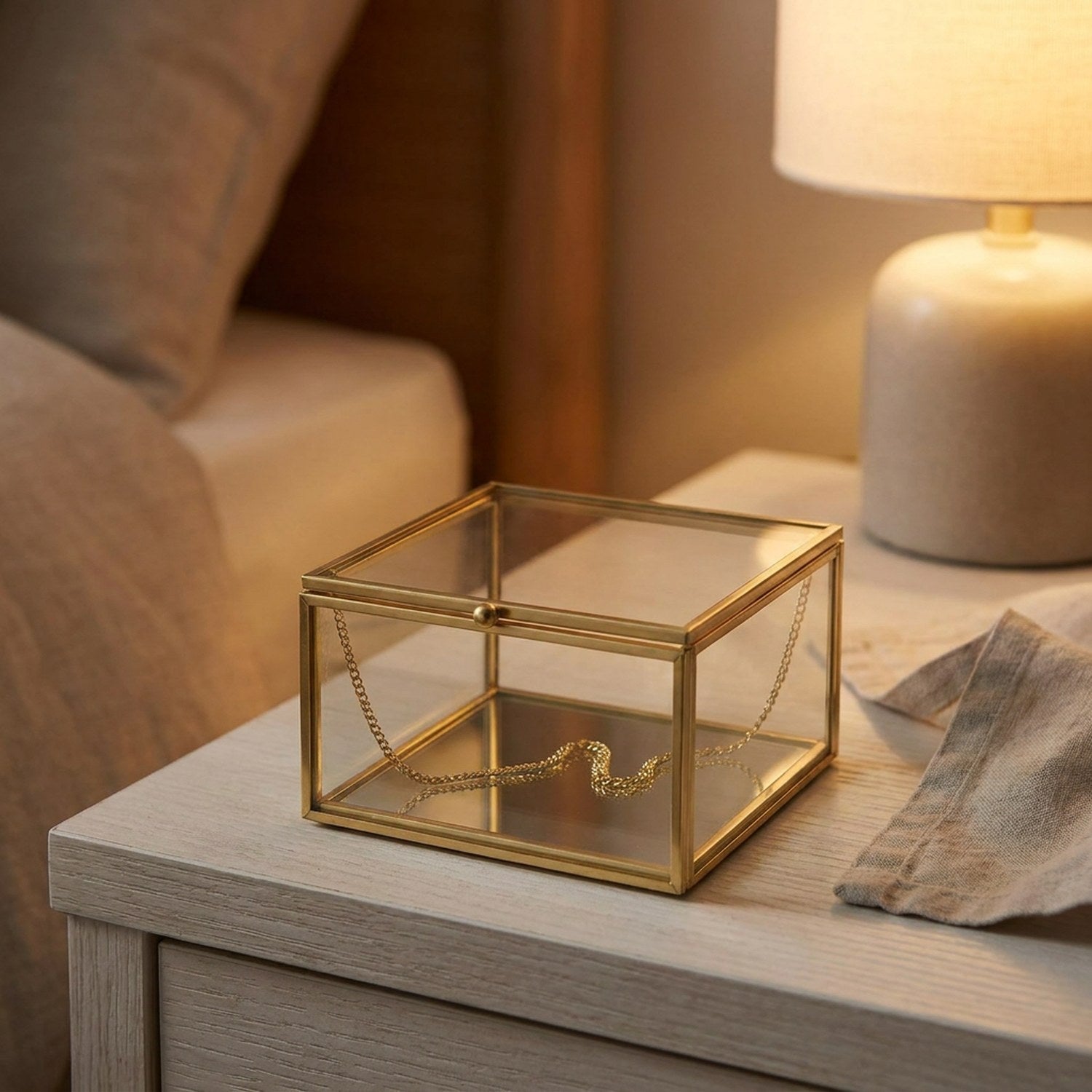 Boîte à bijoux carrée en verre fermée sur une table de nuit avec une lampe douce