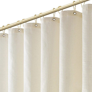 Détail des œillets métalliques et anneaux dorés du rideau de douche
