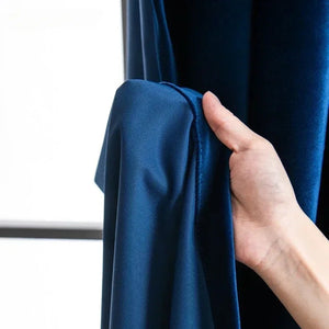 Détail du tissu velours bleu roi épais tenu à la main devant une fenêtre