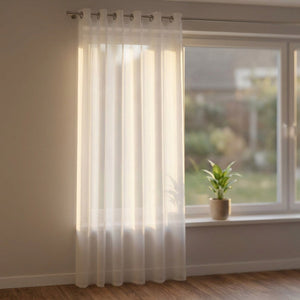 Rideau voilage blanc transparent suspendu à une fenêtre lumineuse de salon