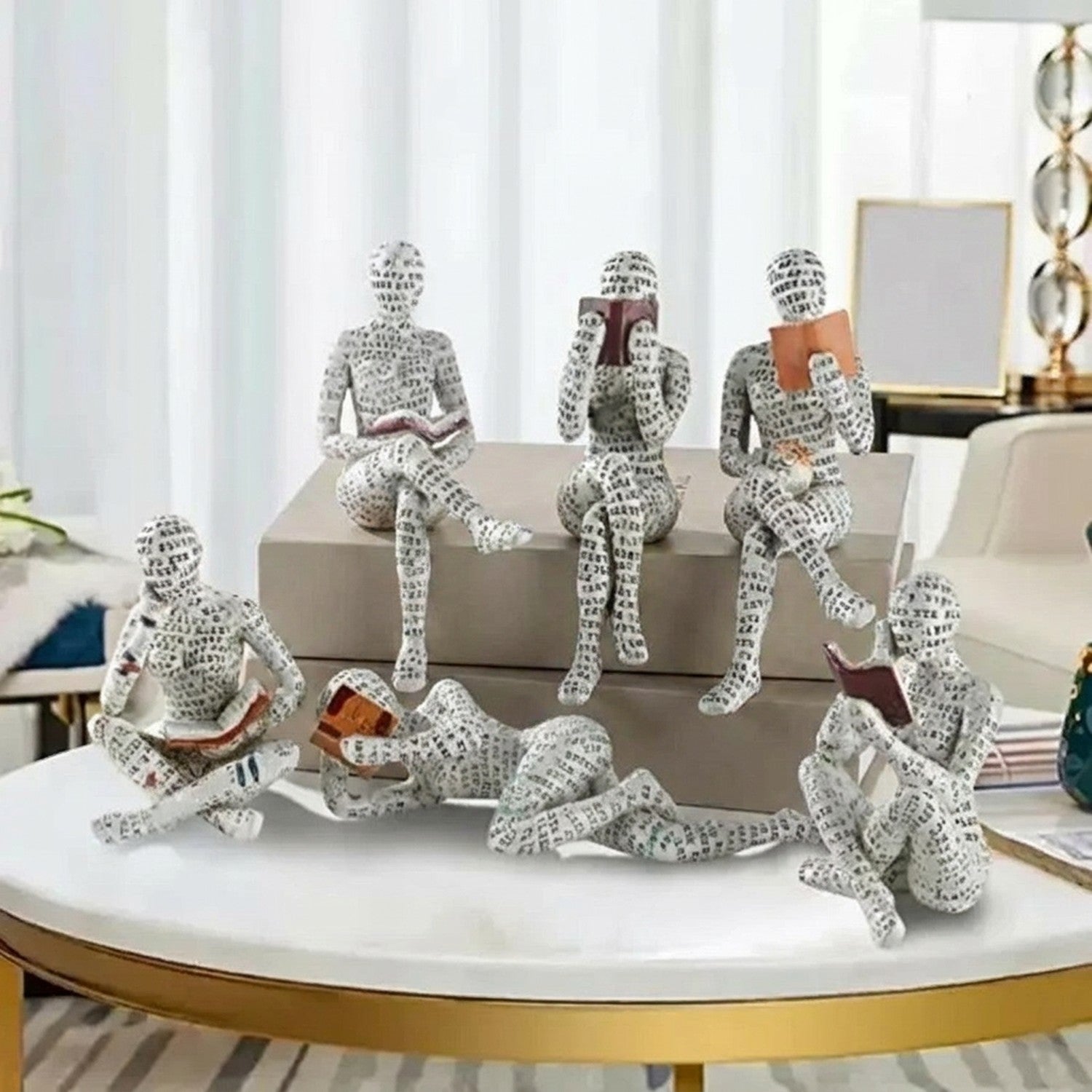 Ensemble de figurines de lecteurs en résine avec motifs typographiques sur table basse