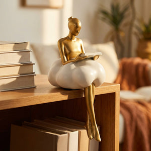 Figurine lectrice en résine dorée avec livre ouvert sur étagère en bois