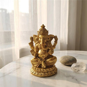 Statue Ganesha dorée posée sur un marbre blanc avec voilage blanc en arrière-plan