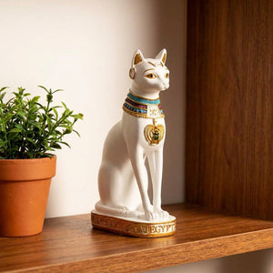 Statuette chat égyptien Bastet en résine blanche avec collier doré sur étagère bois