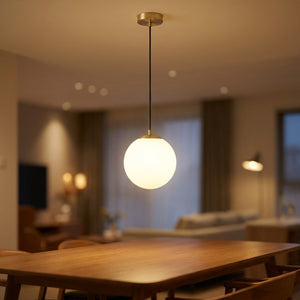 Suspension boule de verre opale avec monture métallique dorée suspendue au-dessus d'une table de salle à manger moderne