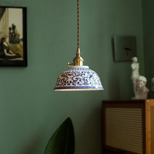 Suspension céramique motif bleu allumée dans un salon vert avec plante