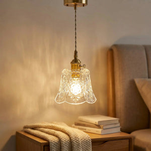Suspension fleur en verre allumée près d'une table de chevet dans une chambre cosy