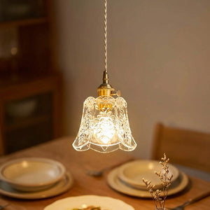 Suspension en verre fleur ciselé doré allumée au-dessus d'une table dans une salle à manger chaleureuse