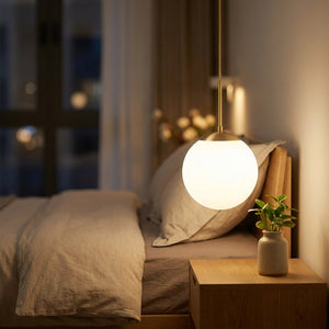 Suspension globe doré allumée près d'un lit dans une chambre cosy