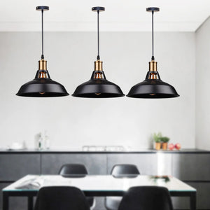 Trois suspensions industrielles noires au-dessus d'un îlot de cuisine lumière allumée