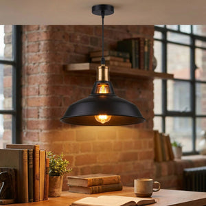 Suspension industrielle allumée dans un bureau style loft avec mur en briques et livres