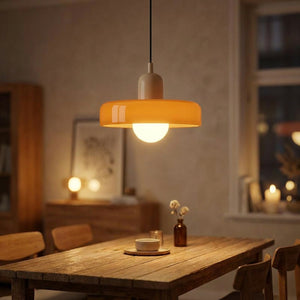 Suspension en verre orange en forme de soucoupe allumée au-dessus d'une table dans un salon chaleureux