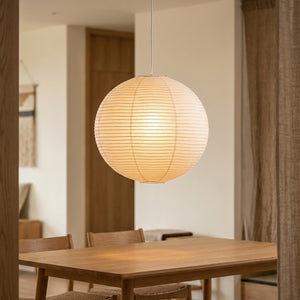 Suspension boule japonaise en papier de riz wabi-sabi, allumée dans une salle à manger Japandi