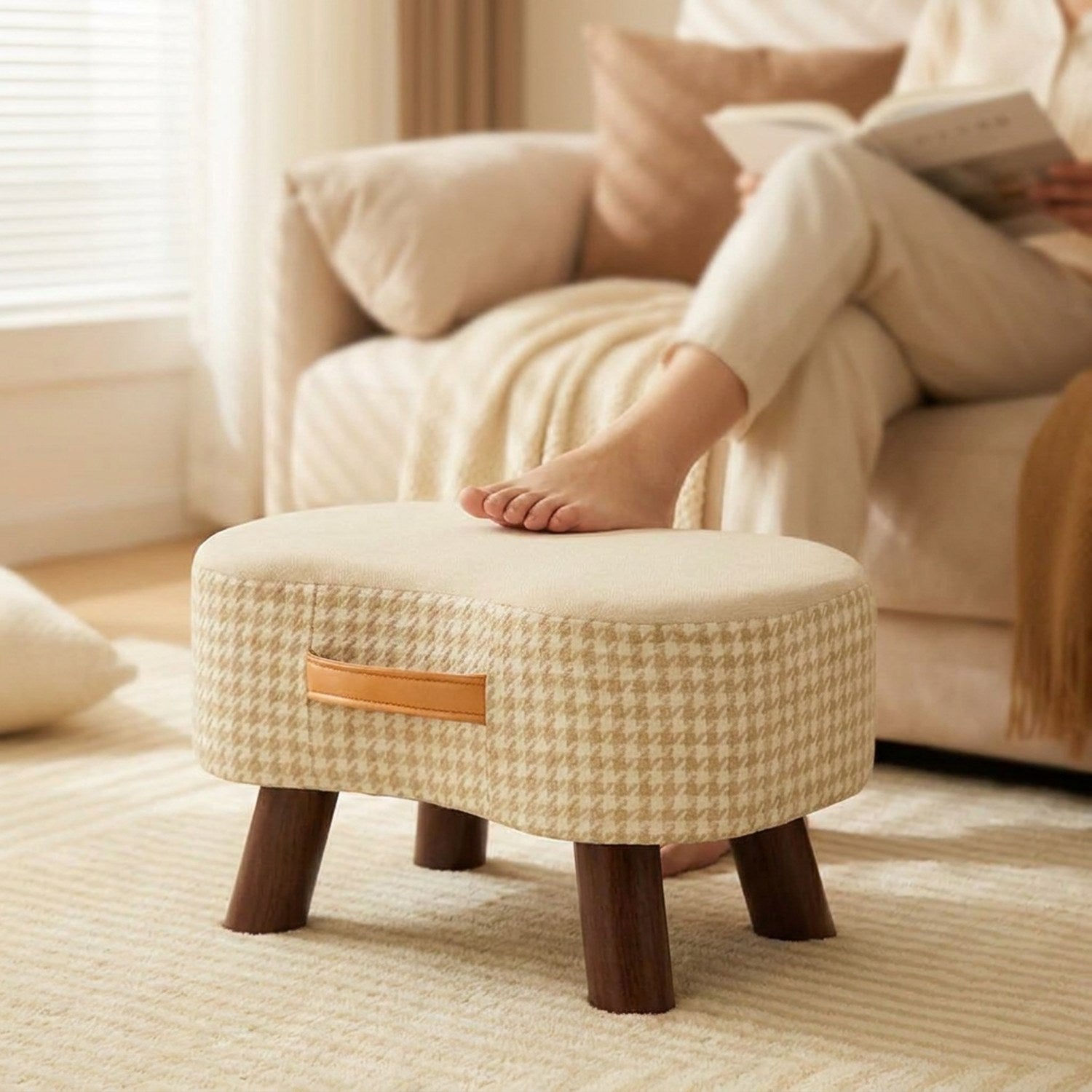 Pied posé sur le tabouret beige pendant une lecture au salon