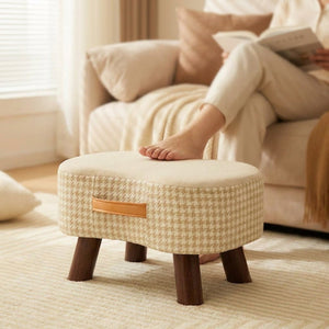 Pied posé sur le tabouret beige pendant une lecture au salon