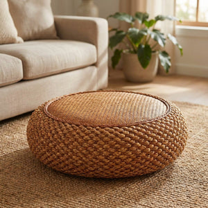 Tabouret pouf rond en jacinthe d'eau tressée posé sur un tapis dans un salon lumineux bohème