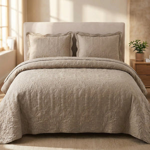 Couvre-lit matelasse taupe au motif damasse en relief sur un lit avec deux taies assorties dans une chambre chaleureuse